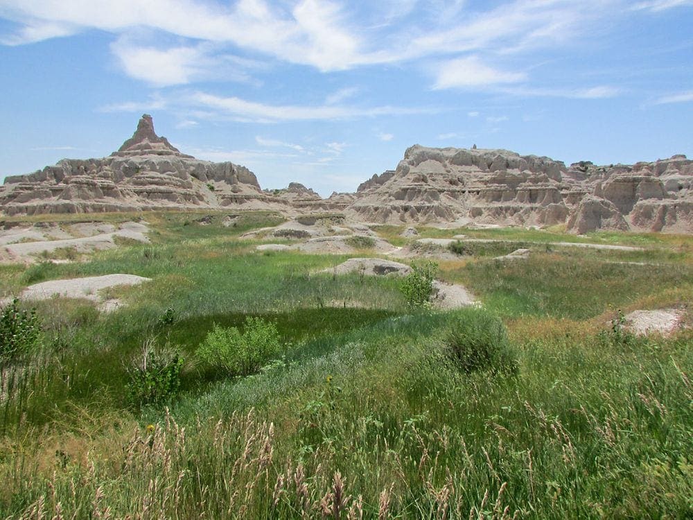 A scenic image of grass and cliffs in the Badlands National Park, a beautiful scene on your Family-Friendly Itinerary to the Badlands.