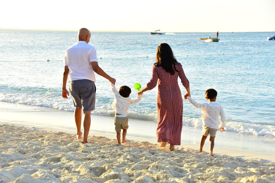 Two parents holding hands with their two kids as they walk along a beach in Turks and Caicos.