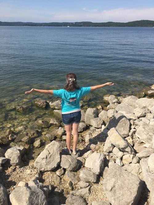 A woman holds her arms outstretched will looking at Table Rock Lake on a sunny day.