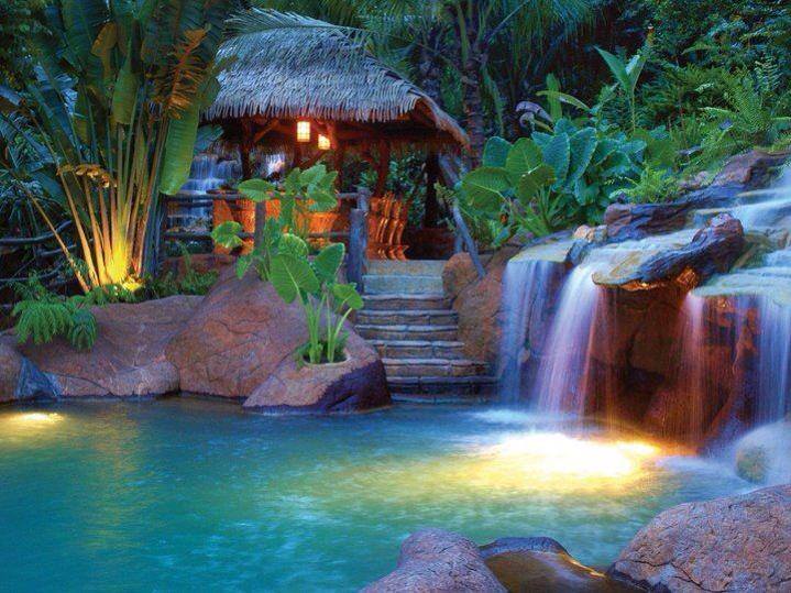 The pool at The Springs Resort & Spa at Arenal, with a sweeping waterfall and covered cabana in the background.