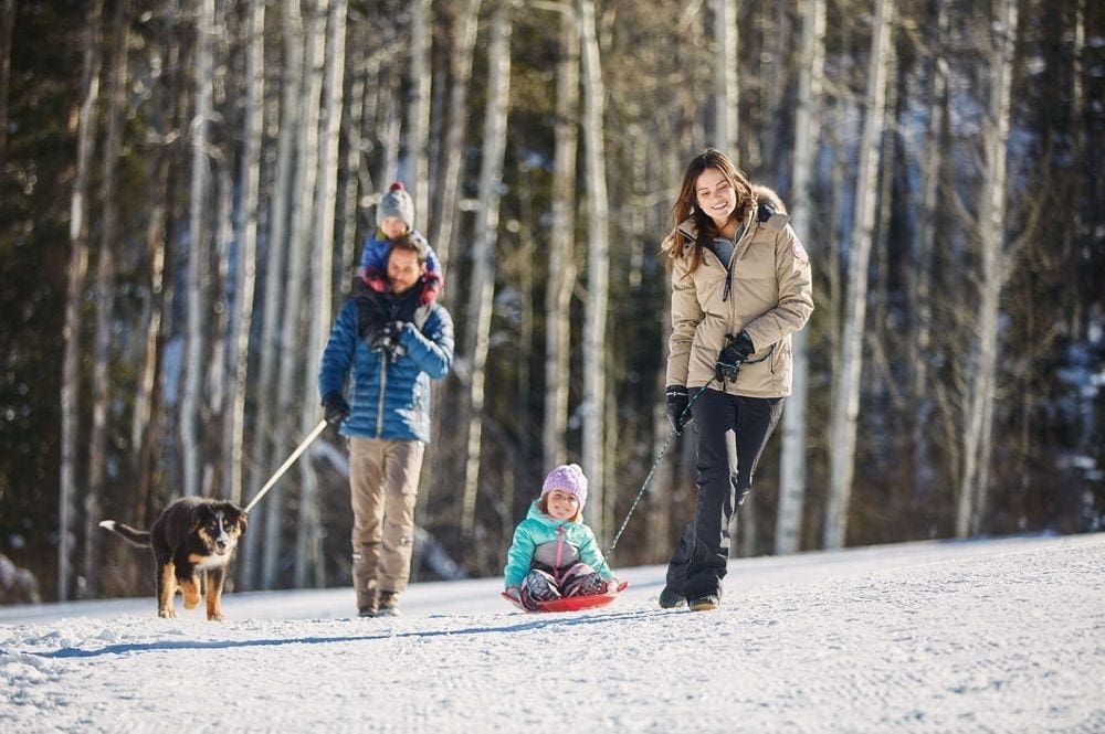 Two parents walk with their two kids and a dog while exploring The Viceroy Snowmass Luxury Hotel & Resort.