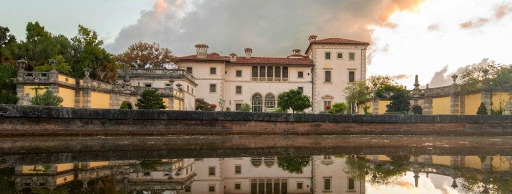 Vizcaya Museum and Gardens estate during sunset across from the large pond in front of the property.