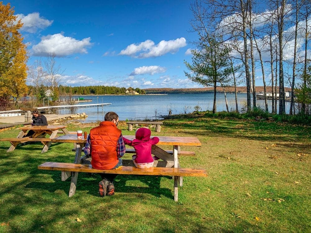 A dad and his daughter sit at a picnic table enjoying lunch in Door County.