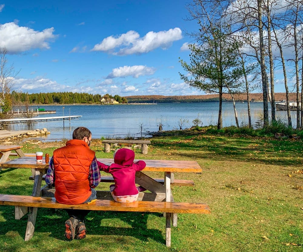 A dad and his daughter sit at a picnic table enjoying lunch in Door County.