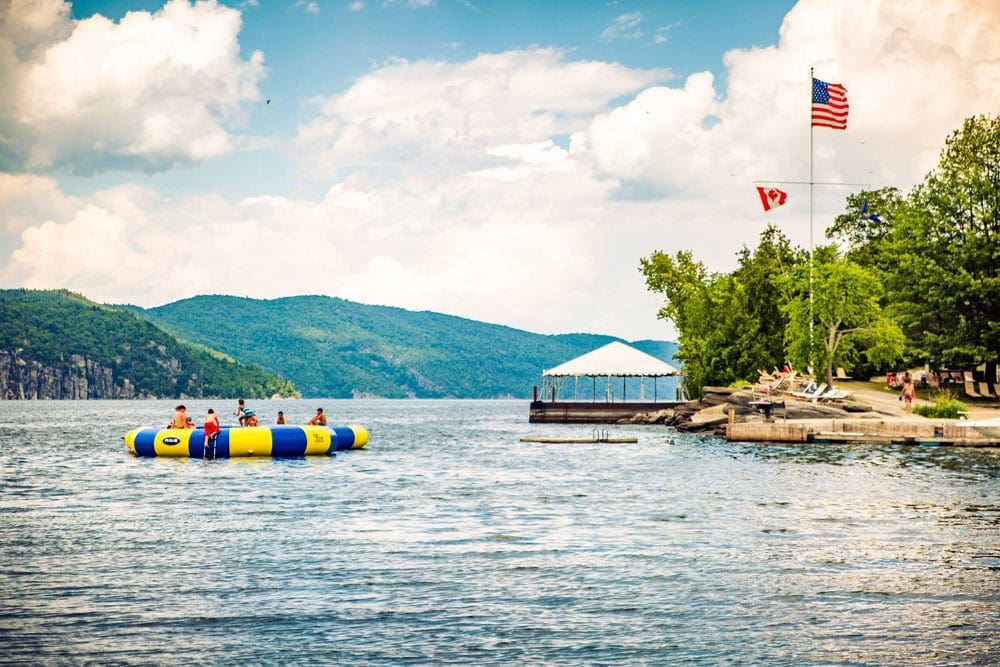 Several kids play on a large floatation device off-shore from Basin Harbor.