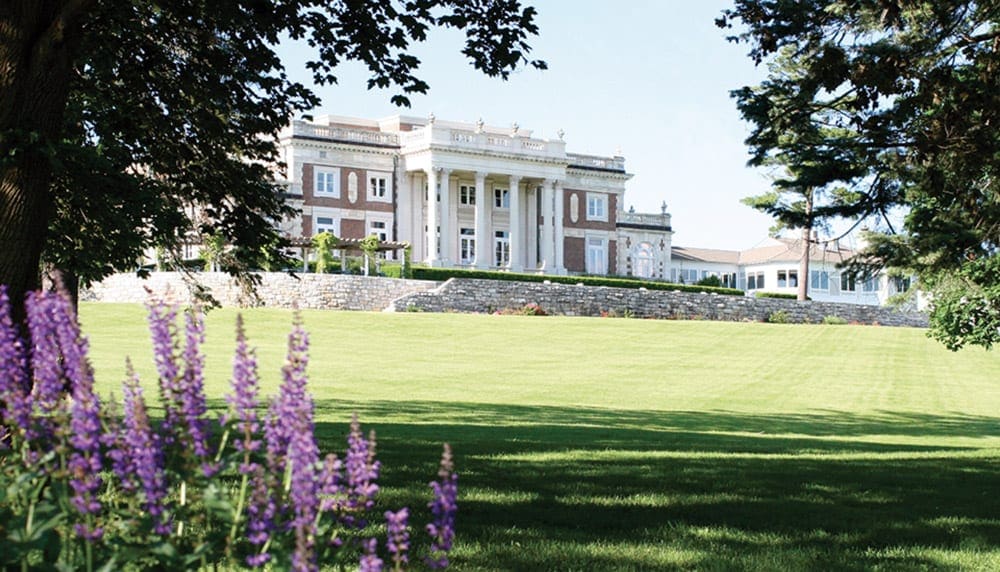 Start your mom's weekend getaway at Canyon Ranch, whose entrance is shown here across a green, grassy field on a sunny day.