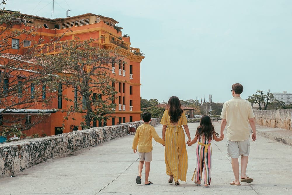 A family of four walks hand in hand in the Old City of Cartagena.