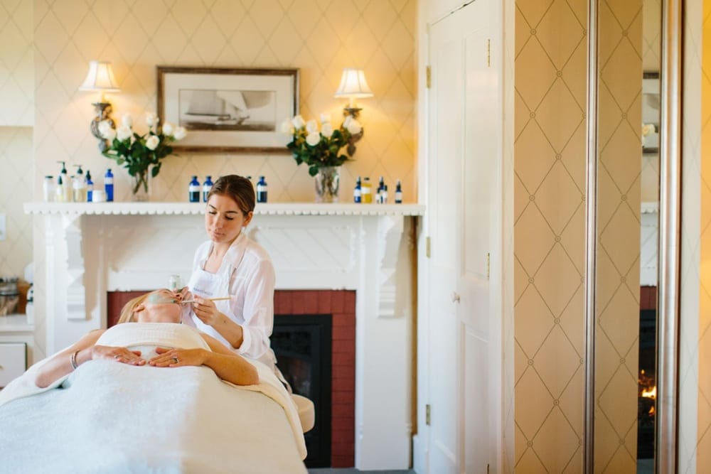 Inside the spa at the Castle Hill Inn, one of the best mom's weekend getaway locations, where a staff member is doing a facial on a guest.