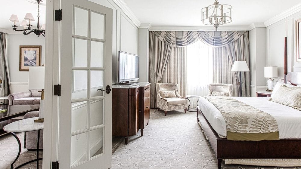 Inside a beautiful and bright room at the Charleston Place, A Belmond Hotel, Charleston, featuring a bed, chairs and other furniture.