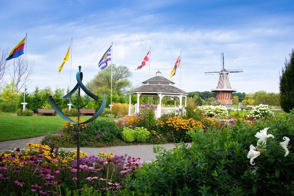 A colorful garden in Holland, Michigan, featuring a gazebo, flags. and a windmill.