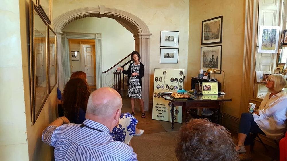 A tour guide leads a tour at the Edmondston-Alston House, while several guests listen.