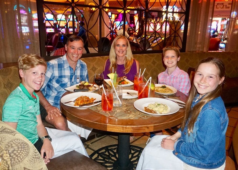 Family of man, woman, two boys and a girl having a fancy dinner in a hotel restaurant. 