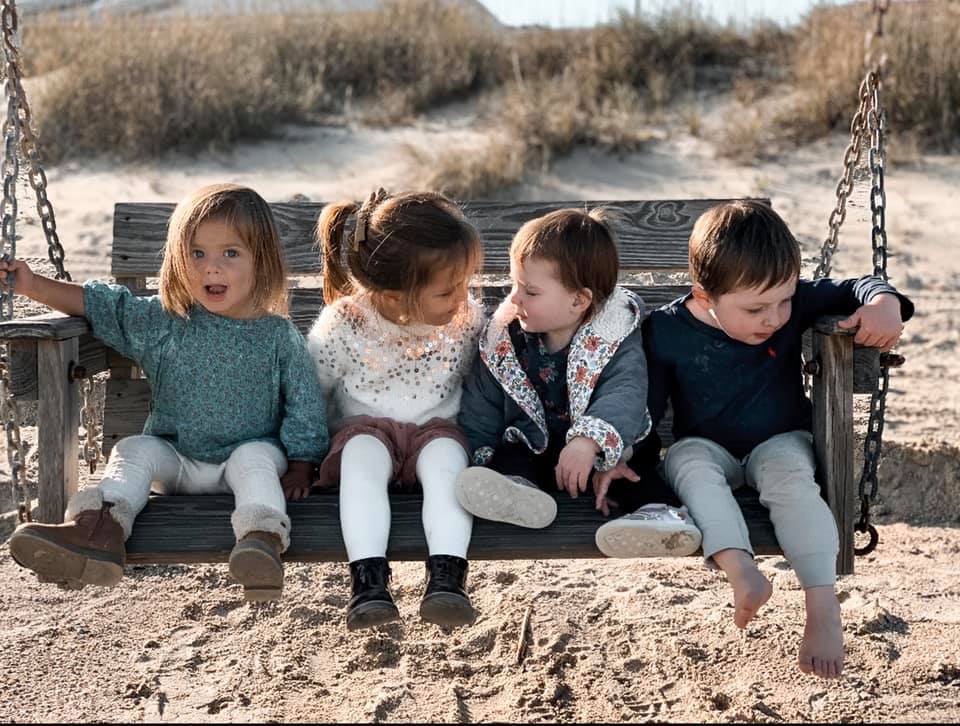 Four kids enjoy a swing in the sand on Tybee Island.