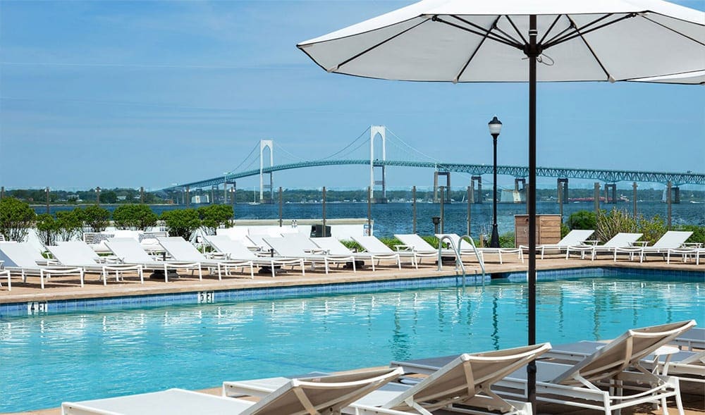 Several white loungers await guests along the outdoor pool at Gurney’s Newport Resort & Marina, one of the best beach resorts in the Northeast for families.