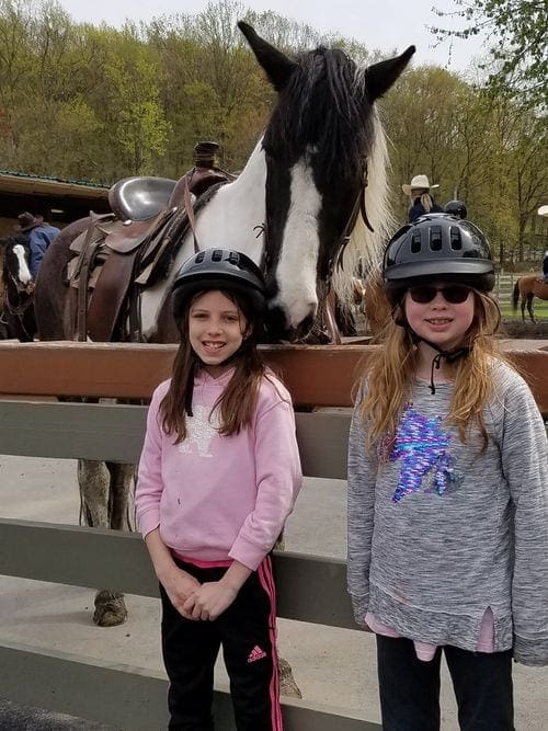 Two girls stand with a horse before a ride at the Rocking Horse Ranch Resort.
