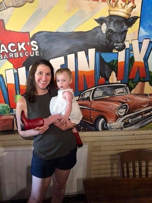 A mom holds her young toddler while enjoying a BBQ place in Austin.