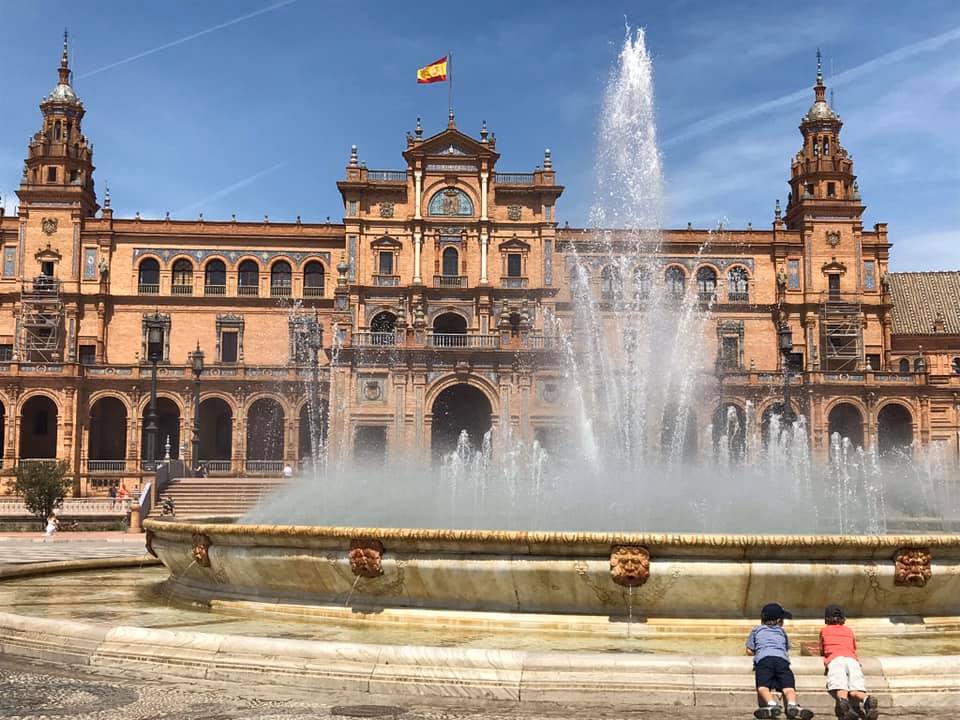 Two kids enjoy the views of a large fountain in Seville.