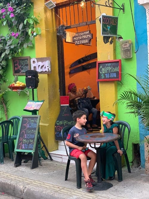 Two kids laugh at a cafe table in Cartagena.
