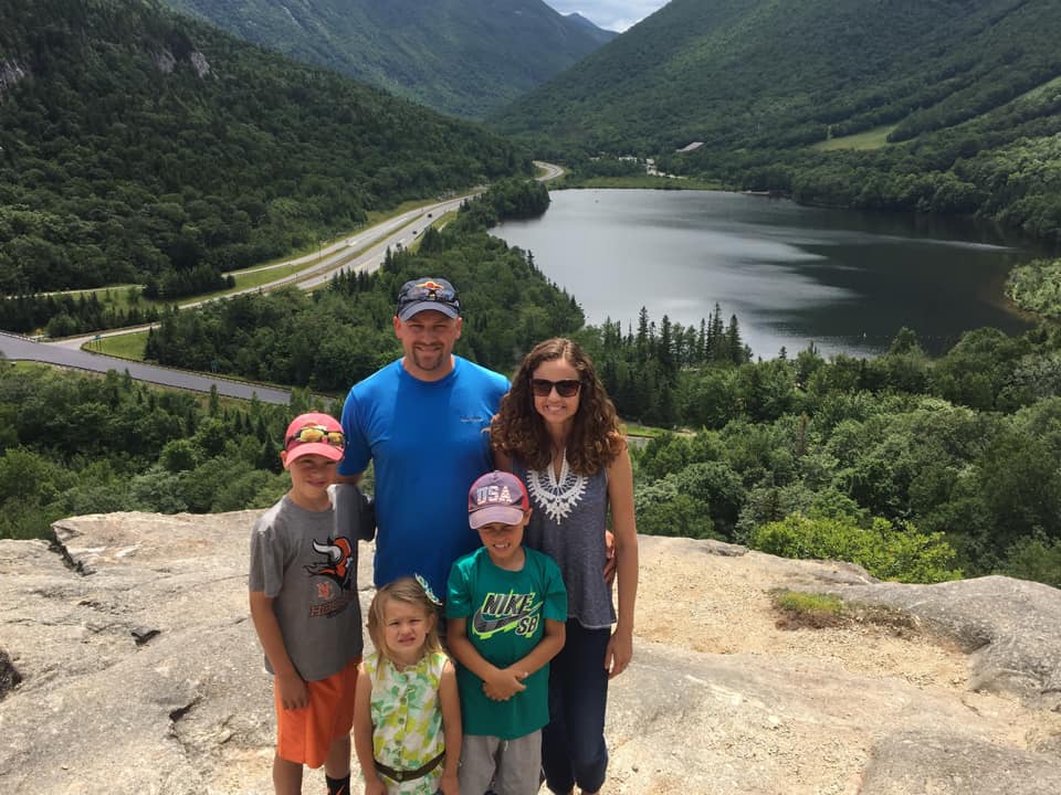 A family of five stands together atop a rock formation in the White Mountains in New Hampshire.