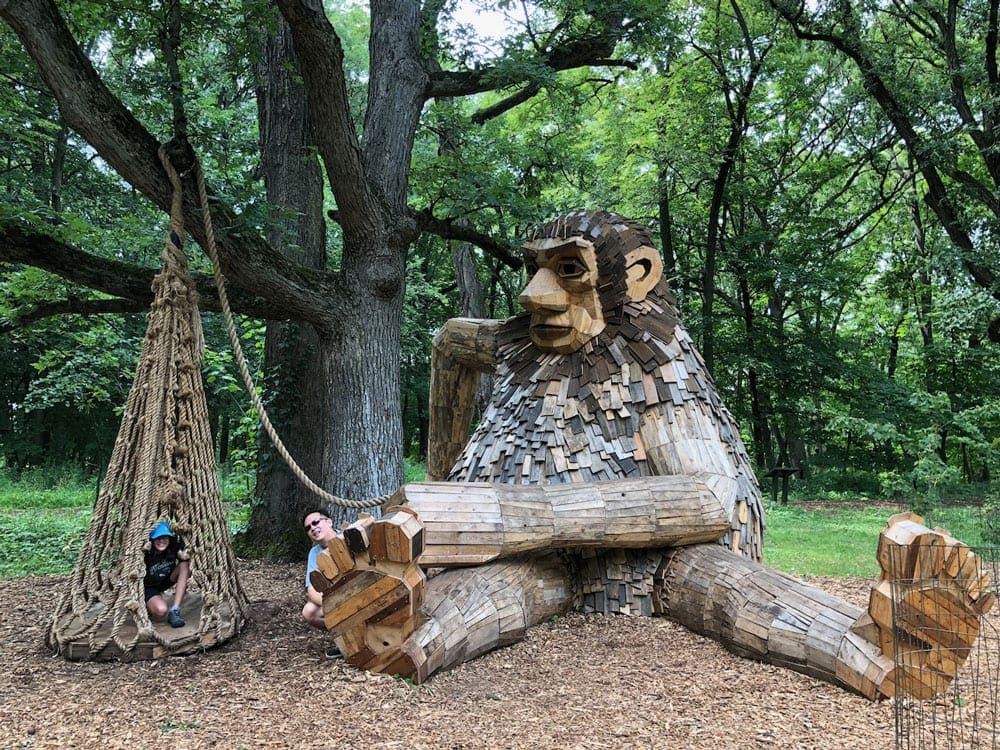 A young child explore a park with a huge wooden troll at the Morton Arboretum, one of the best kids activities in Chicago.