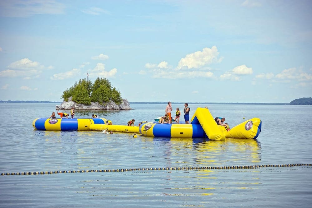 A large blue and yellow inflatable on the water off-shore from The Tyler Place Family Resort, one of the best summer lake resorts in the Northeast for families.