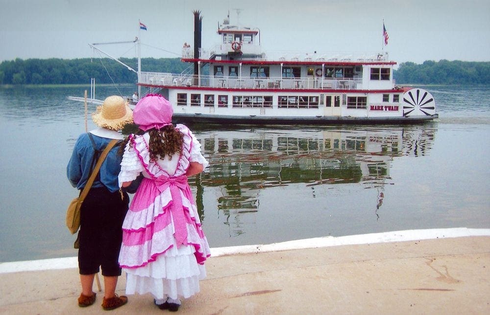 Two costumed locals look at the Mark Twain River Boat in Hannibal, MO.
