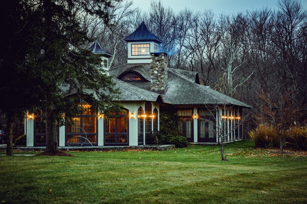 One of the main buildings at the Winvian Farm, one of the best themed hotels on the East Coast for families, lit up during dusk, giving it a charming allure.