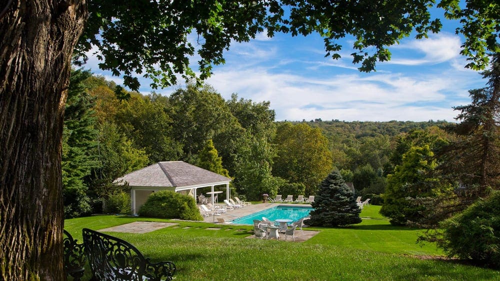 A pool and beautiful pool deck on a sunny day on the grounds of Mayflower Inn & Spa, Auberge Resorts Collection, one of the best mom's weekend getaway locations.