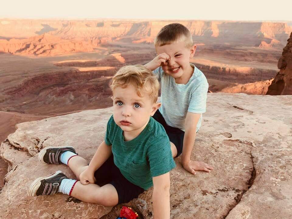 Two kids sit together along a rock ledge within Dead Horse Point State Park, one of the best things to do in Moab with kids.