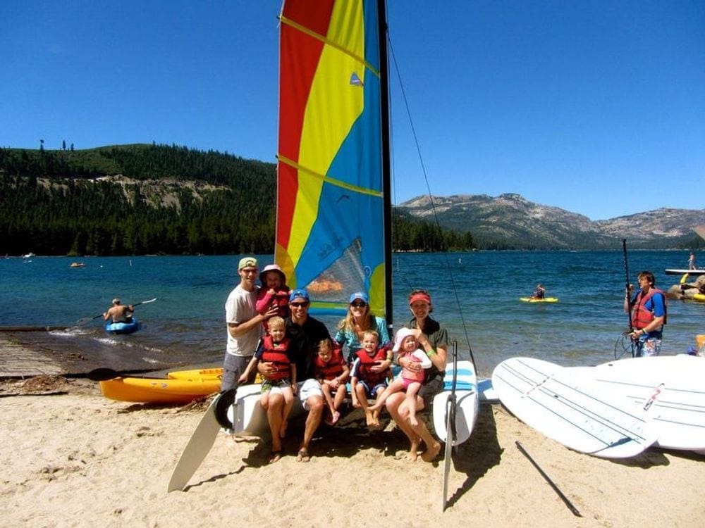 Several families sit together, posing on a sail boat, while enjoying a sunny day on Lake Tahoe.