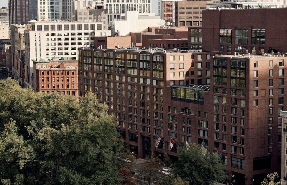 A view of the Four Seasons Hotel Boston, surrounded by other tall buildings and trees.