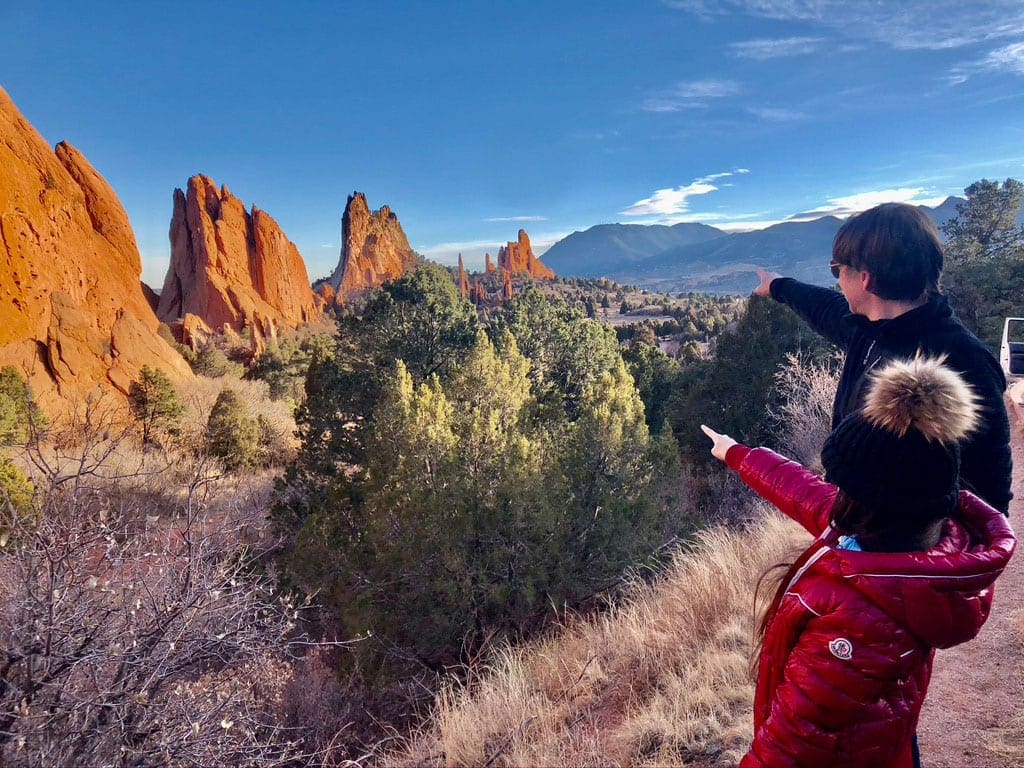 A young girl and her dad point across a valley while exploring the Garden of the Gods, one of the best things to do in Colorado Springs with kids.