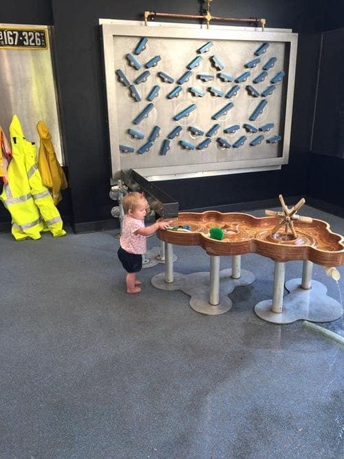 A toddler girl explors a hand-on exhibit at the Minneapolis Children's Museum, one of the best things to do in Minneapolis with kids.