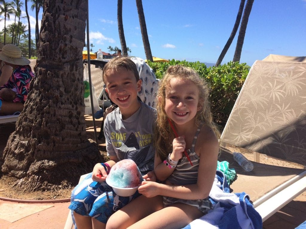 Two kids enjoy a pool-side snow cone at Grand Wailea Maui, A Waldorf Astoria Resort, one of the best family hotels in Maui.