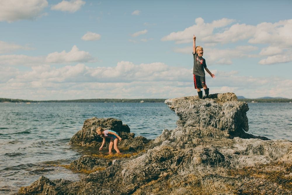 Two young children explore tidepools while explore Bar Harbor, Maine.