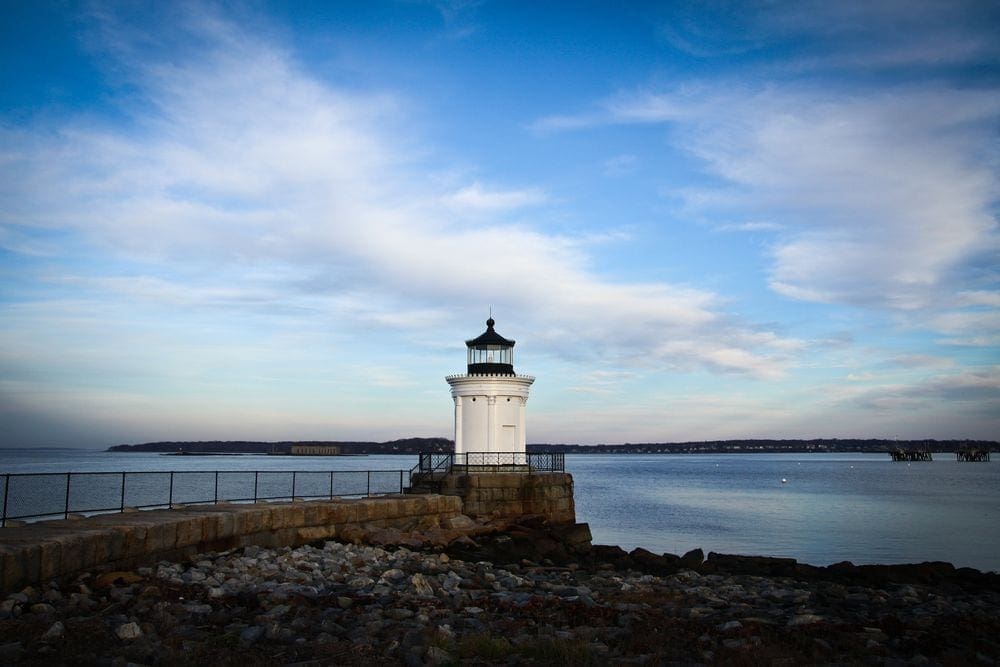 A lighthouse stands proudly on a sunny day off the coast from South Portland, one of the best places to visit in Maine with kids.