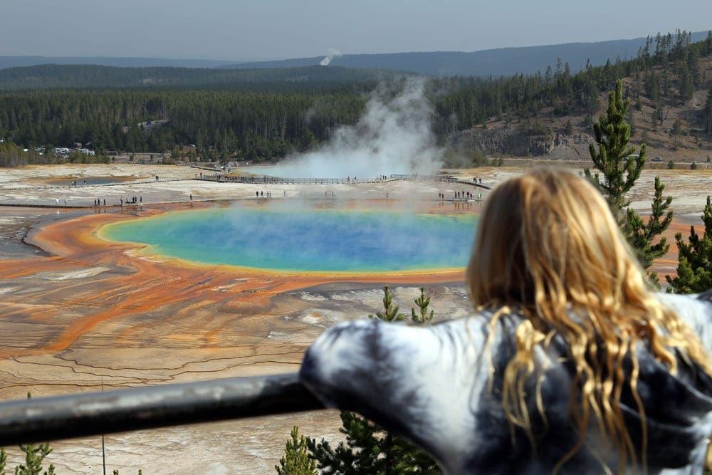 A young girl overlooking the Grand Prismatic Spring, one of the best places to visit on a Yellowstone itinerary with kids. 