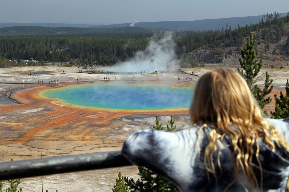 A young girl overlooking the Grand Prismatic Spring, one of the best places to visit on a Yellowstone itinerary with kids.