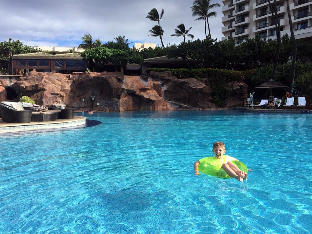 A young boy sits in a yellow swim tube in the pool at 