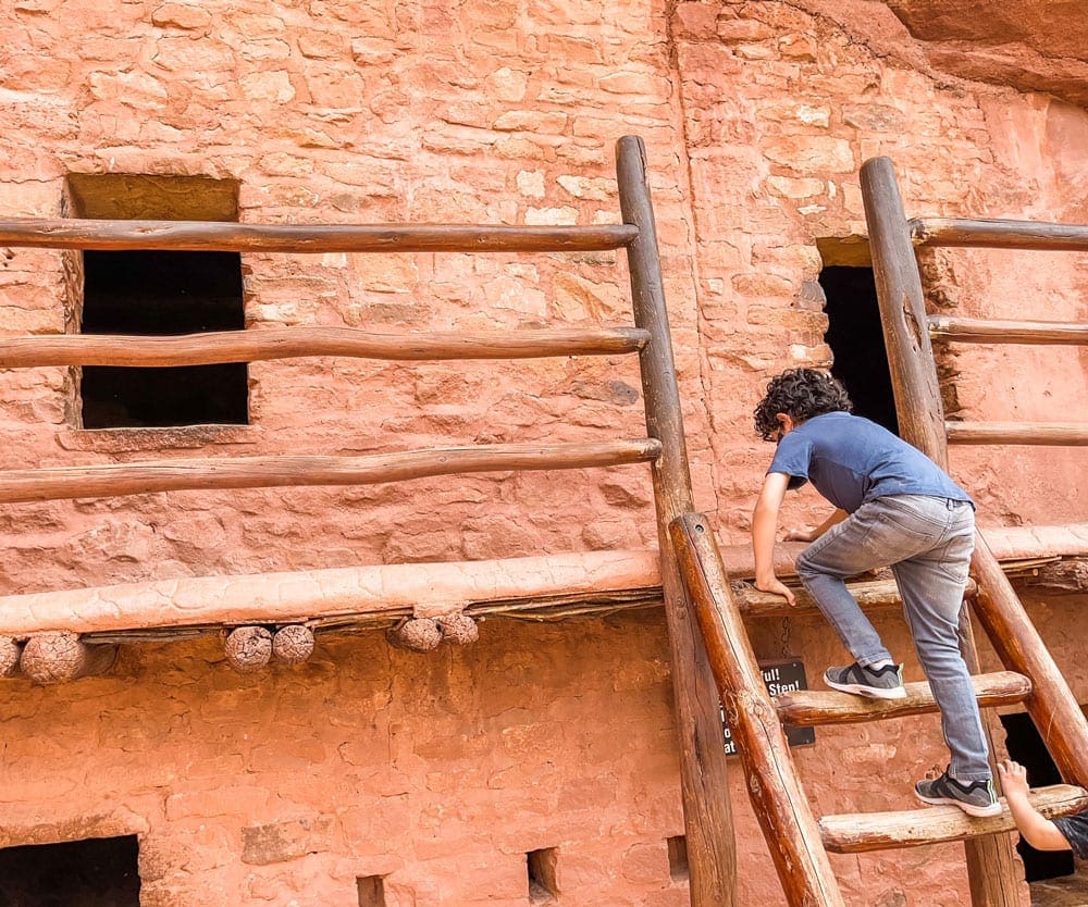 A young boy climbs a ladder at the Manitou Cliff Dwellings, one of the best things to do in Colorado Springs with kids.