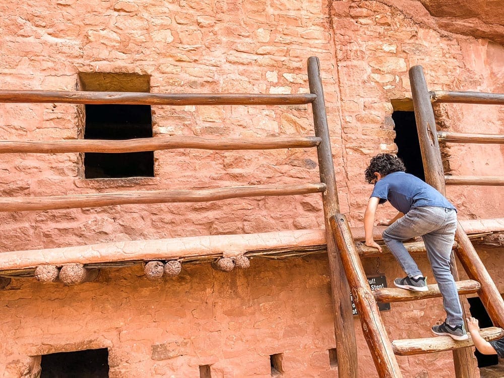 A young boy climbs a ladder at the Manitou Cliff Dwellings, one of the best places to visit on a Colorado Springs itinerary for families with kids. 