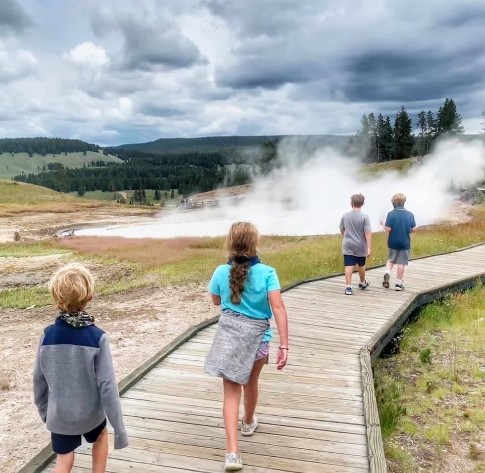 A family with kids walking along the boardwalk in Yellowstone National Park.