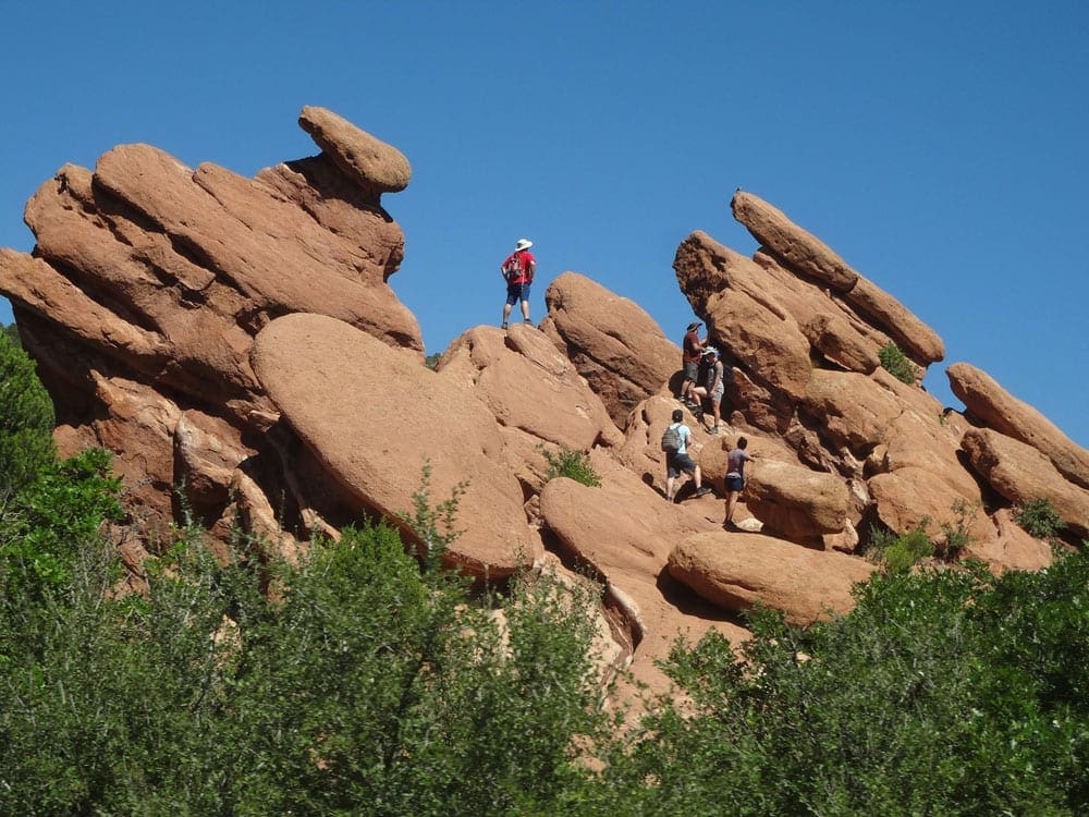 Three people climb amongst the huge bolders at the Garden of the Gods in Colorado.