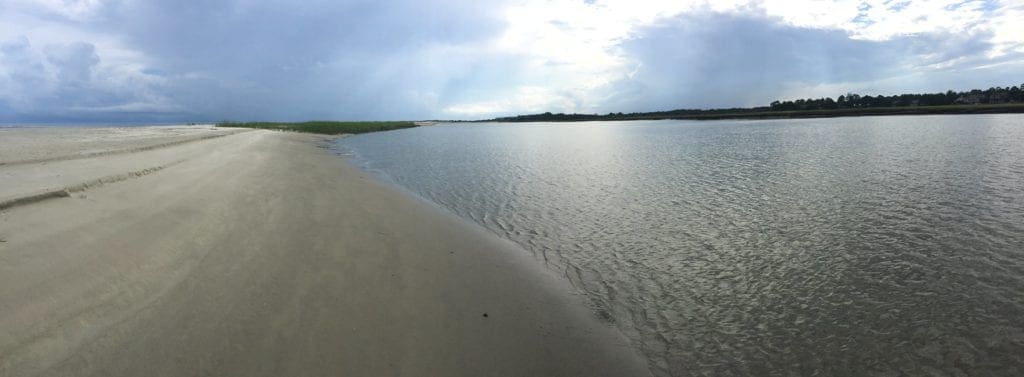 A pristine beach with calm waters on a sunny day.