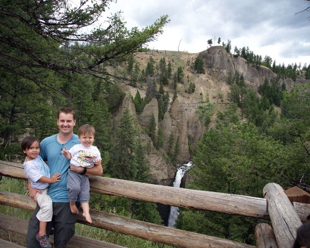 A dad holds two kids while hiking inside Grand Tetons National Park.