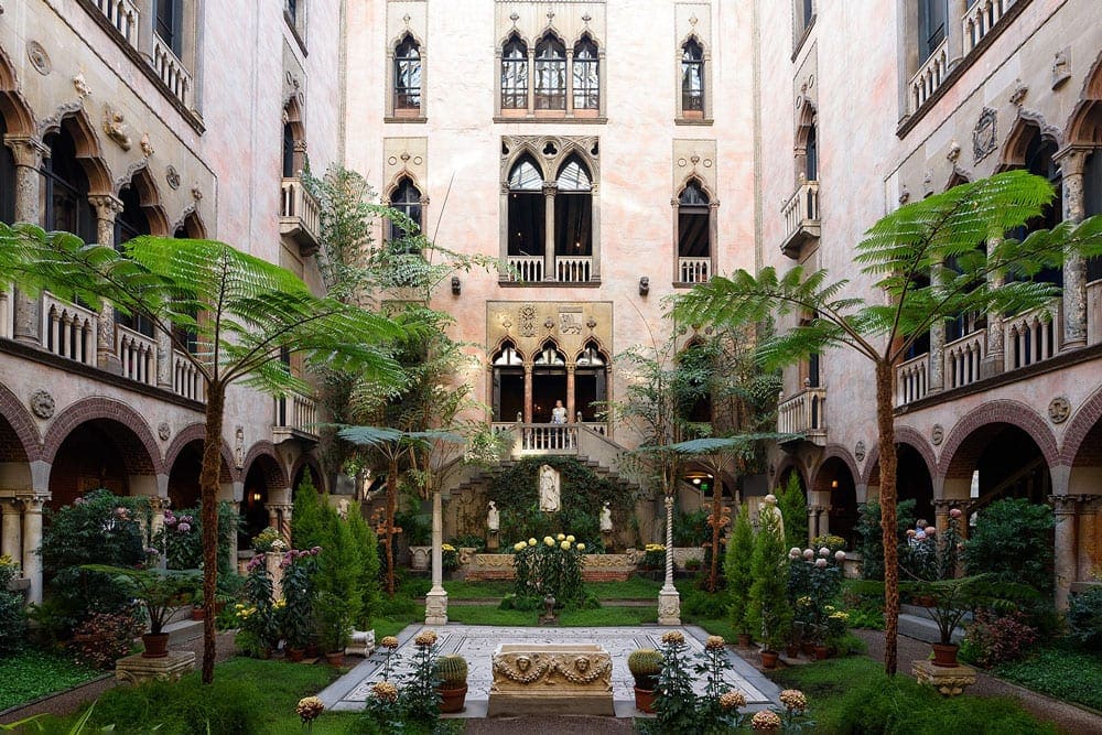 A woman walks out onto a balcony at the Isabella Stewart Gardner Museum, one of the best places to visit on a Boston itinerary for families. 