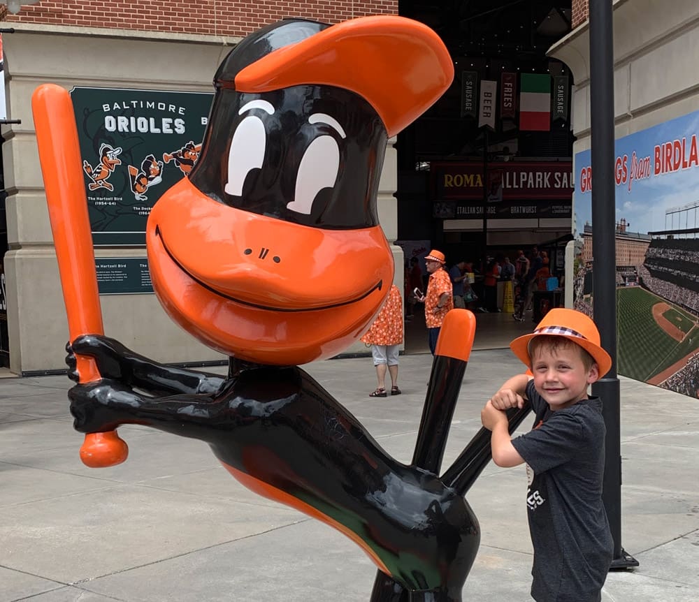 A young boy poses with a statue of a mascot duck in Baltimore, one of the best weekend getaways near DC for families.