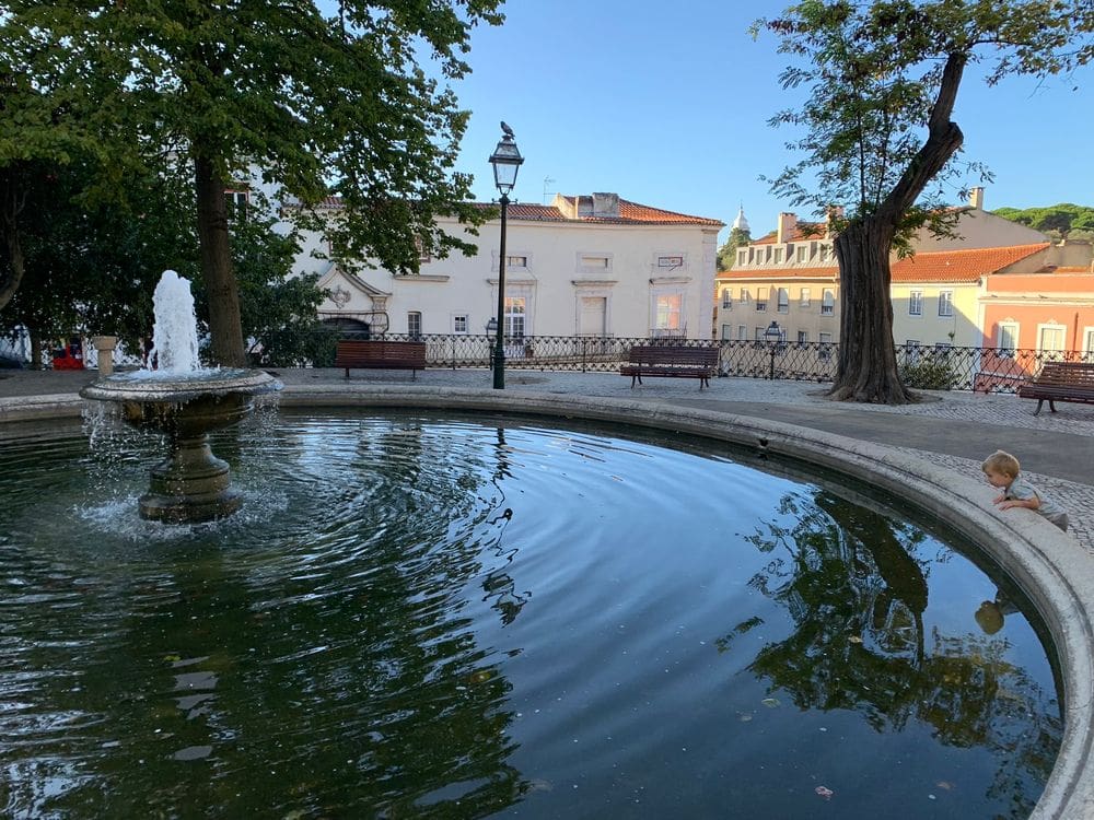 A young boy peers into a fountain in a courtyard in Portugal.