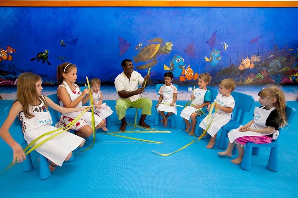 A staff member at the Kurumba Maldives kids club shows kids how to make a craft.