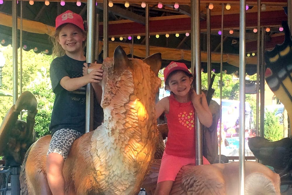 Two kids ride the Rose Kennedy Greenway Carousel, one of the best places to visit on a Boston itinerary for families. 